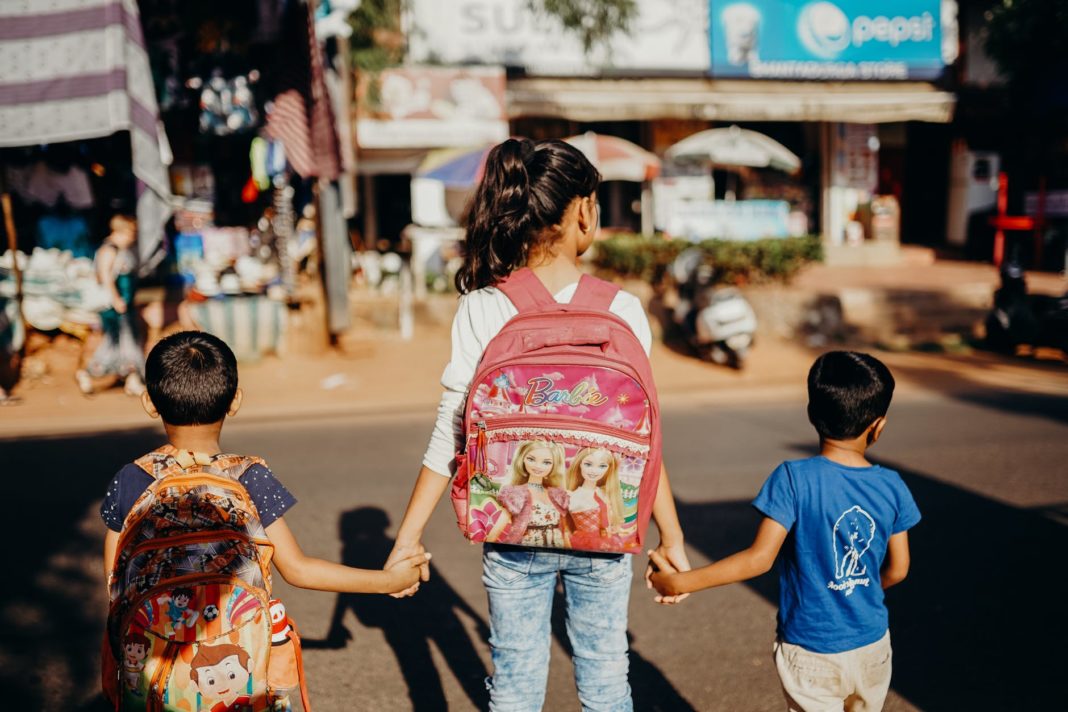 pexels-photo-4427659 woman in blue t shirt carrying red and white backpack walking on street