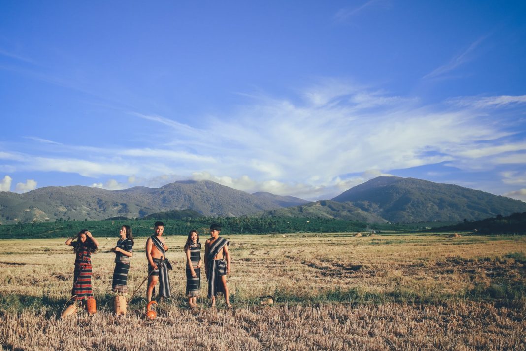 pexels-photo-1679923 five people wearing native apparel standing on brown grassfield under blue and white cloudy sky