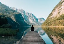 प्रेम नहीं प्रताड़ना a person sitting on wooden planks across the lake scenery